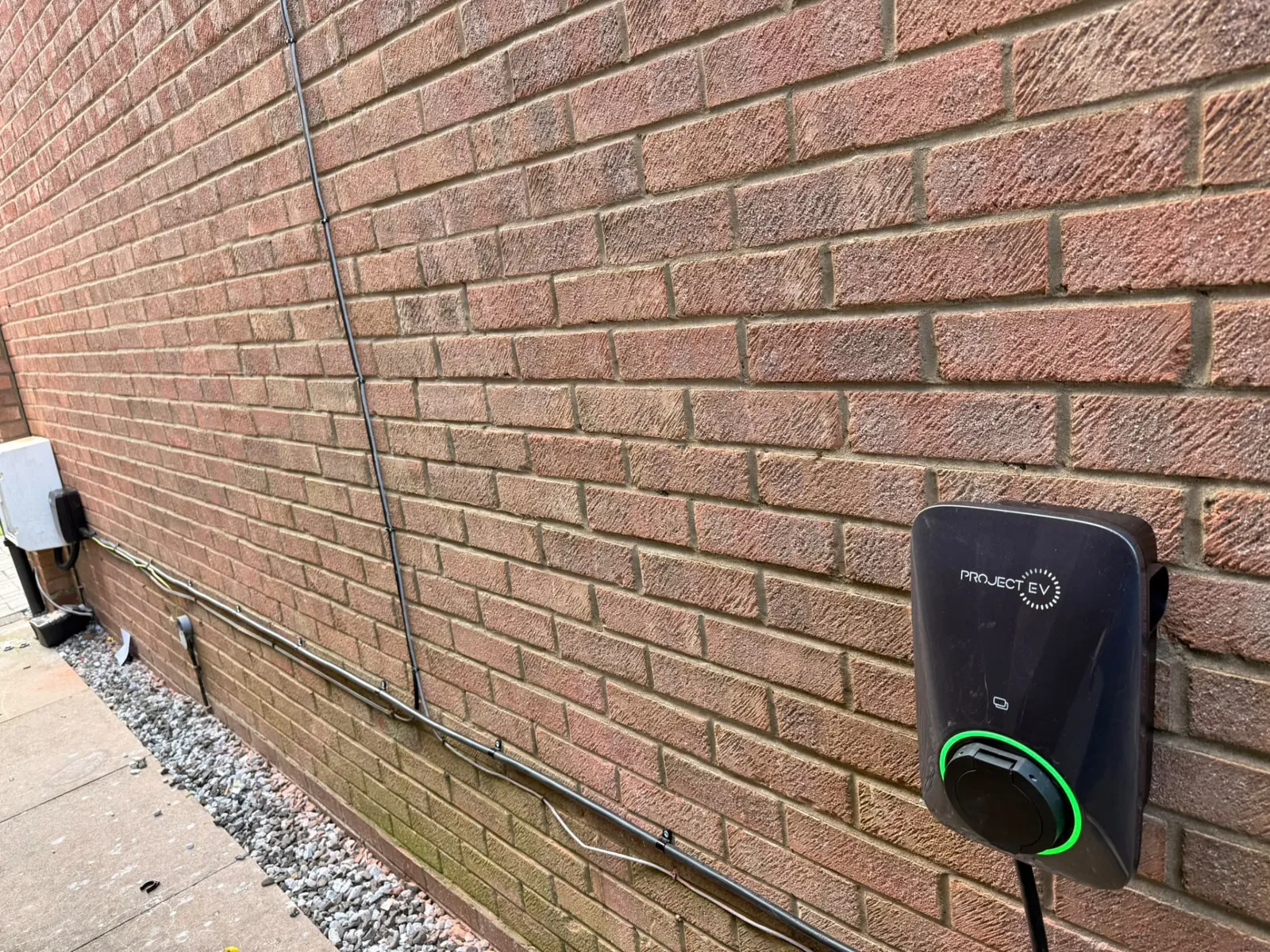 Home EV charger installed on an exterior brick wall