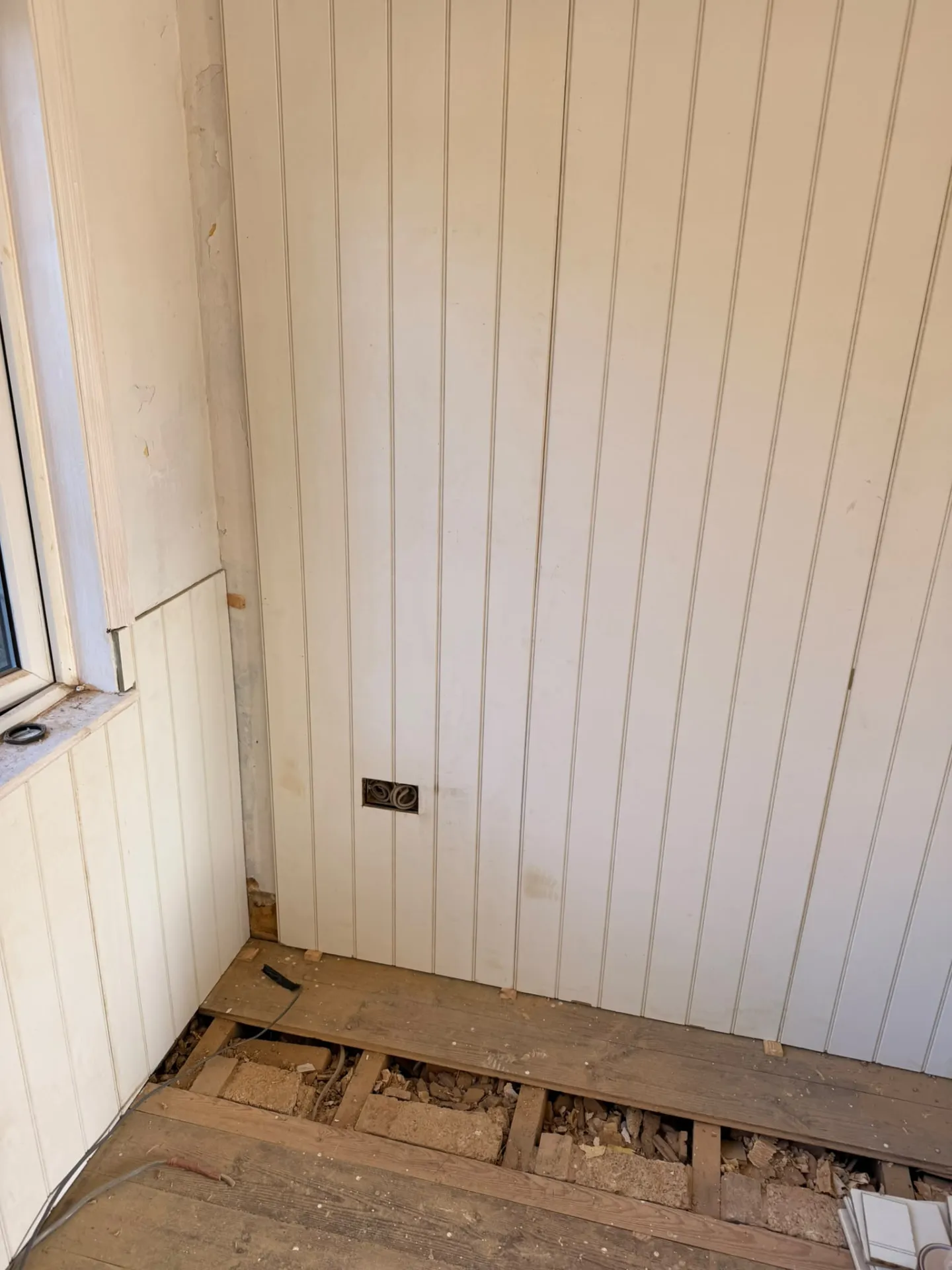 Stripped-back room with lifted floorboards during a house rewire