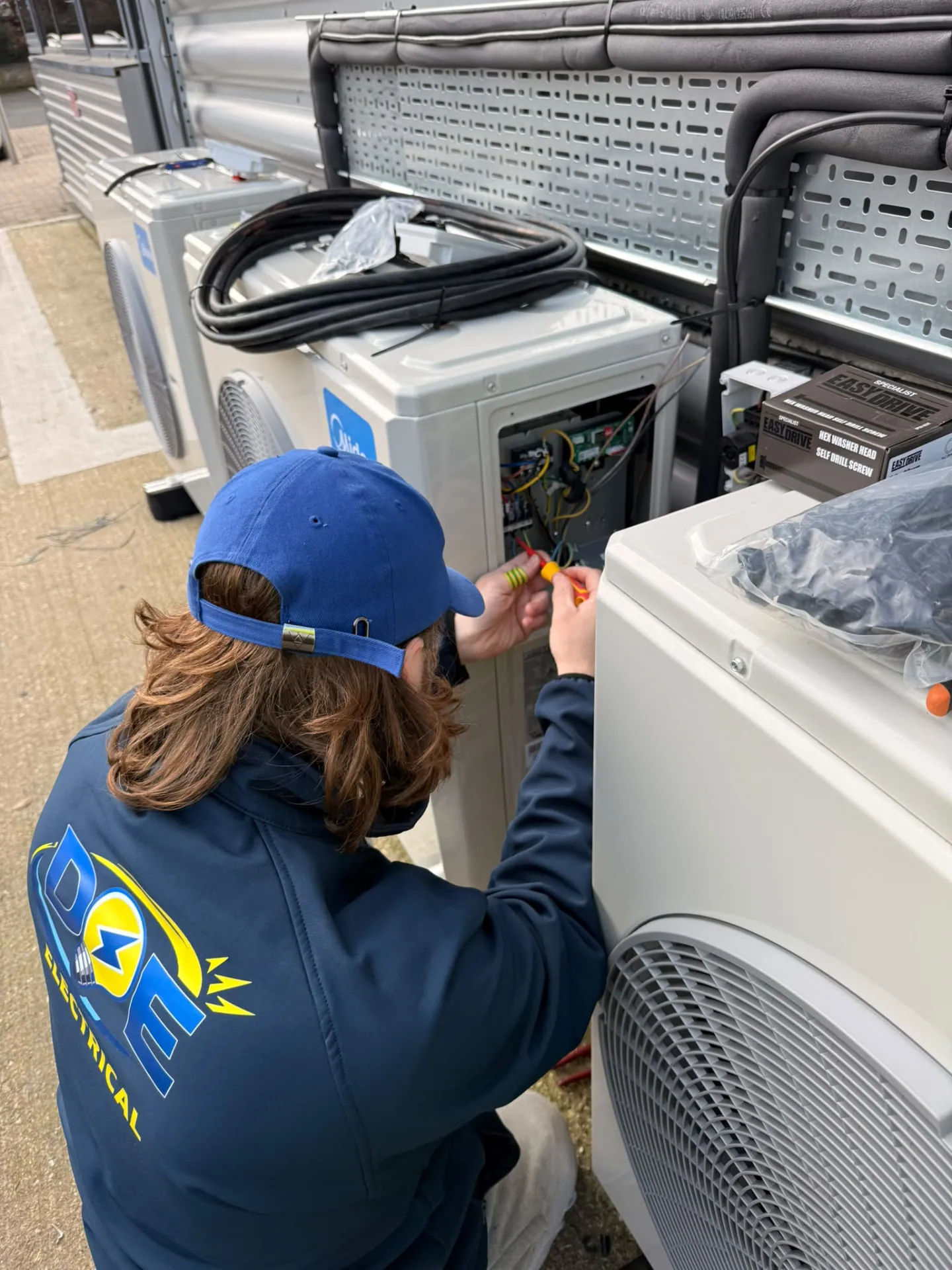 Doe Electrical electrician in branded workwear connecting an air conditioning unit