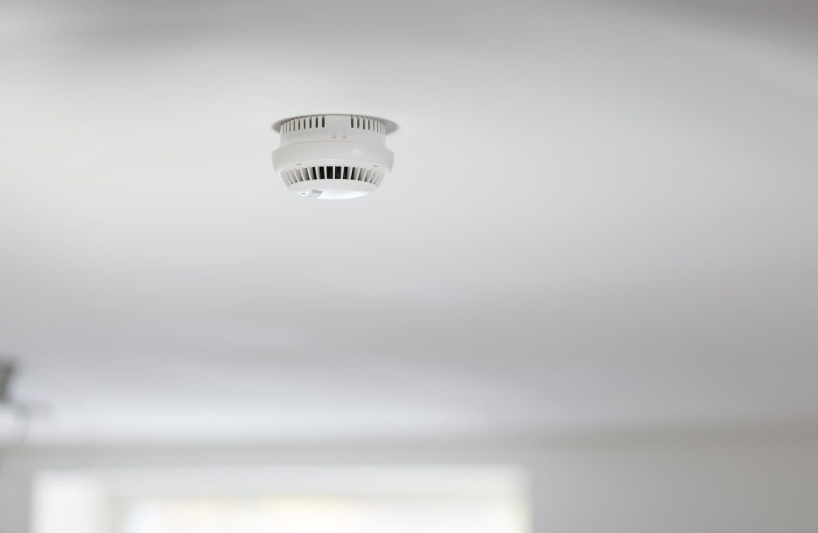 Mains-wired smoke alarm fitted to a white ceiling